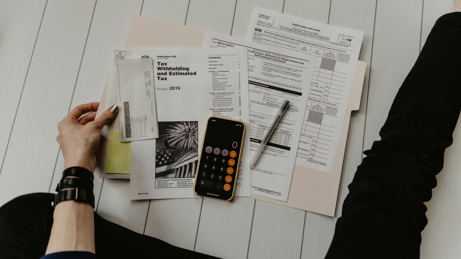 Calculator and payroll paperwork on a desk next to a laptop