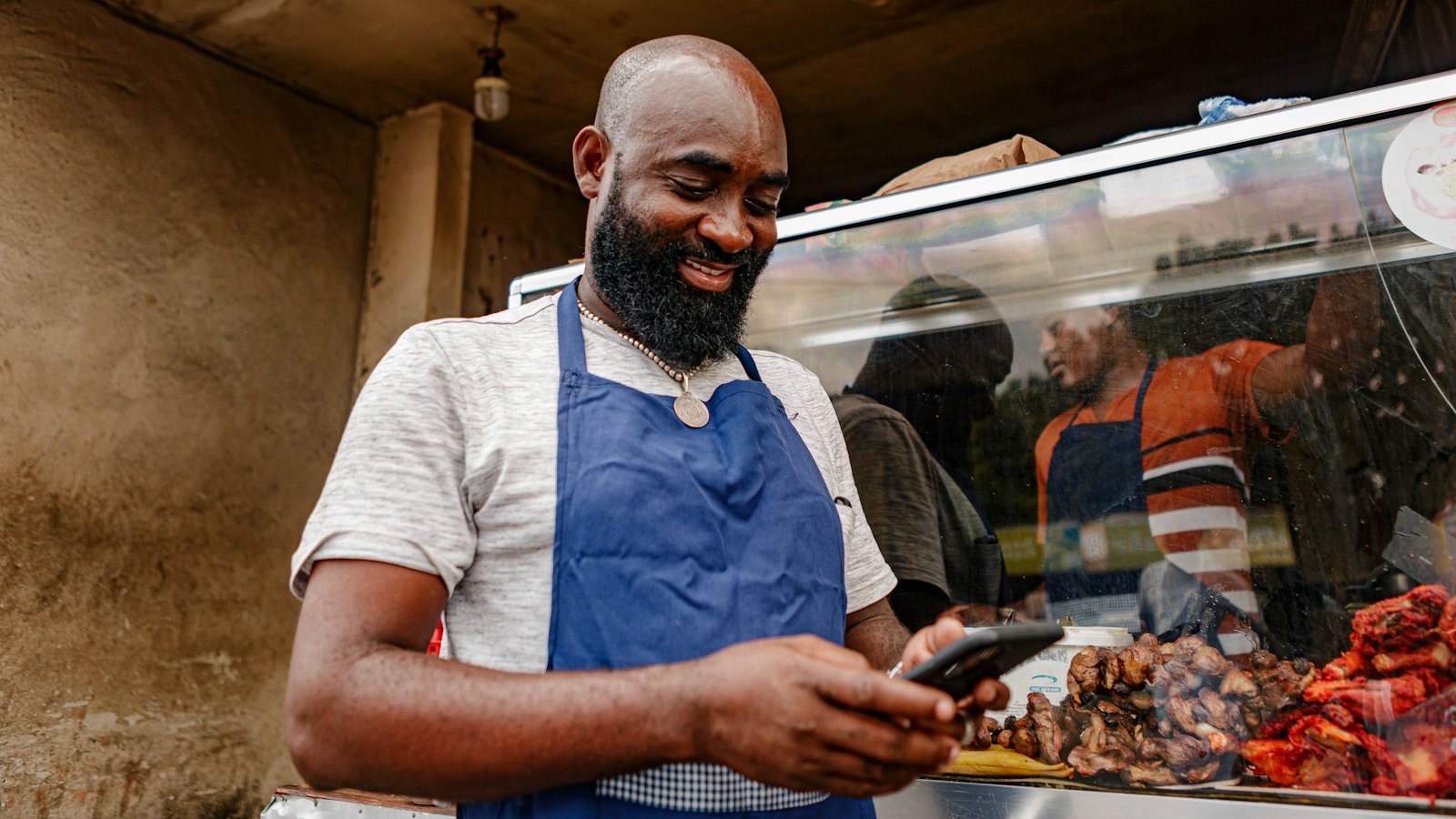 Hospitality worker in an apron checking a shift swap on a smartphone